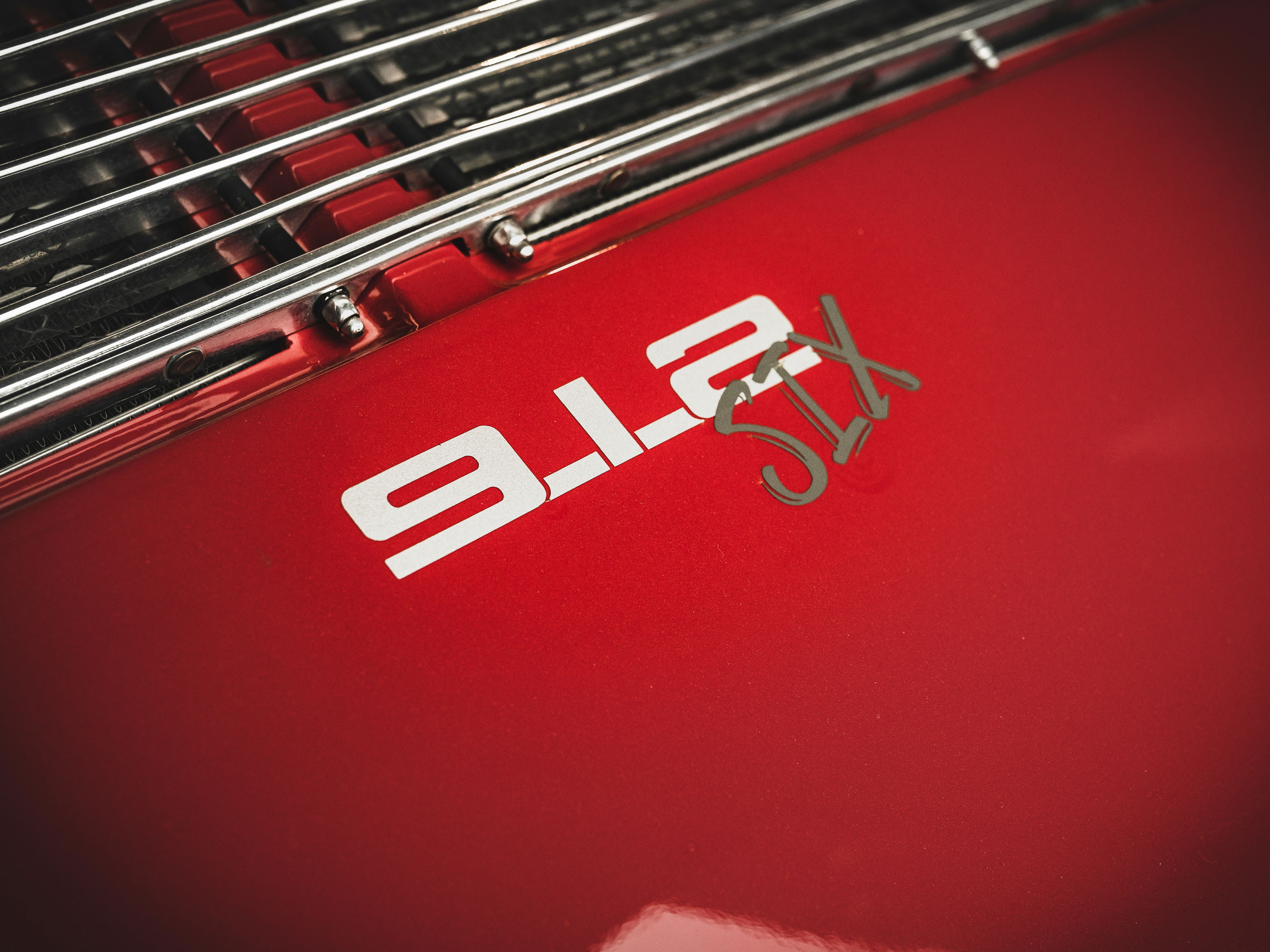 Red Porsche 912 Six rear decklid, showcasing its chrome engine grille and iconic "912 Six" emblem.