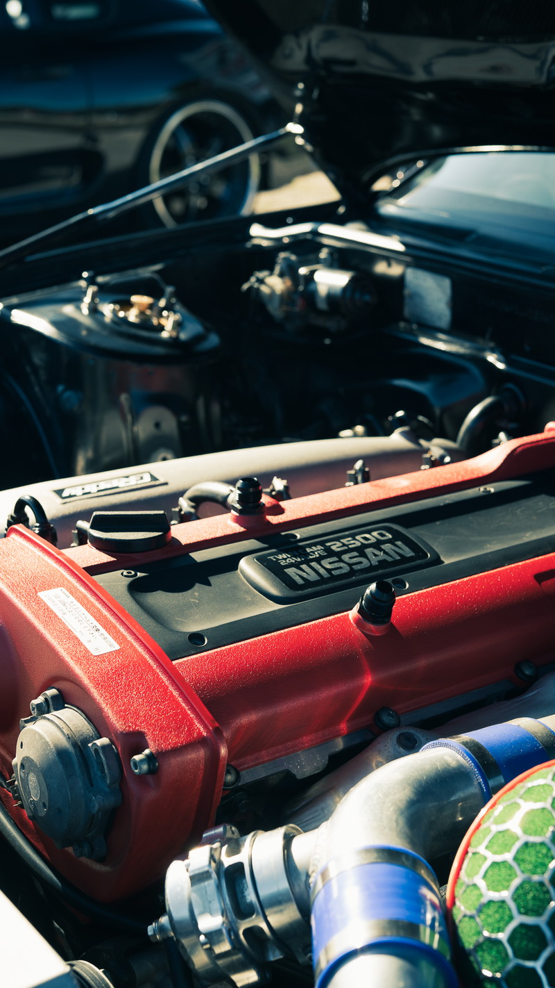 Black Nissan Skyline's custom Nissan RB25 Twin Cam 24V engine. Red valve cover, green filter, blue couplers, polished intake.