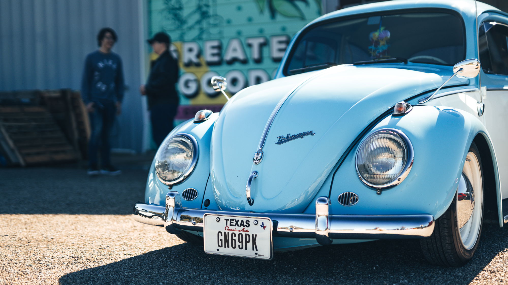 Vintage baby blue VW Beetle, detailed with gleaming chrome trim, Texas plate, and white steelie rims with hubcaps.