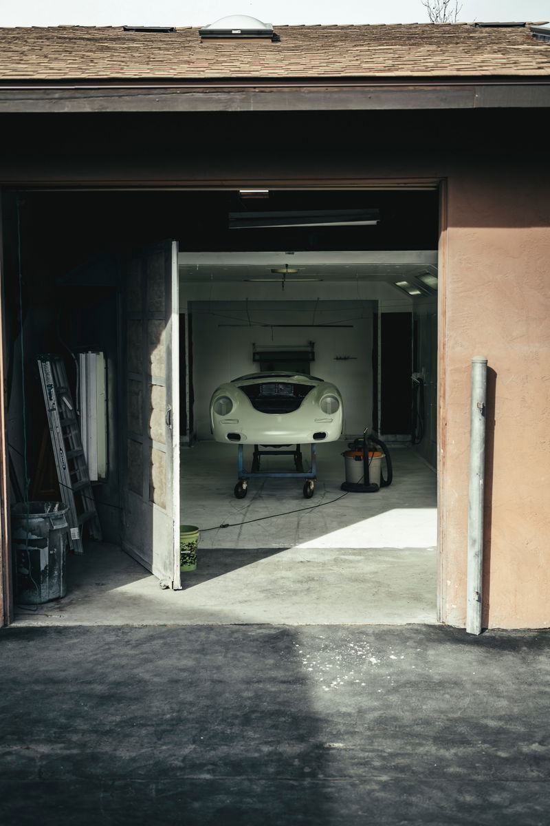 Front view of a creme white Porsche 356 body shell on a workshop cart, ready for restoration.
