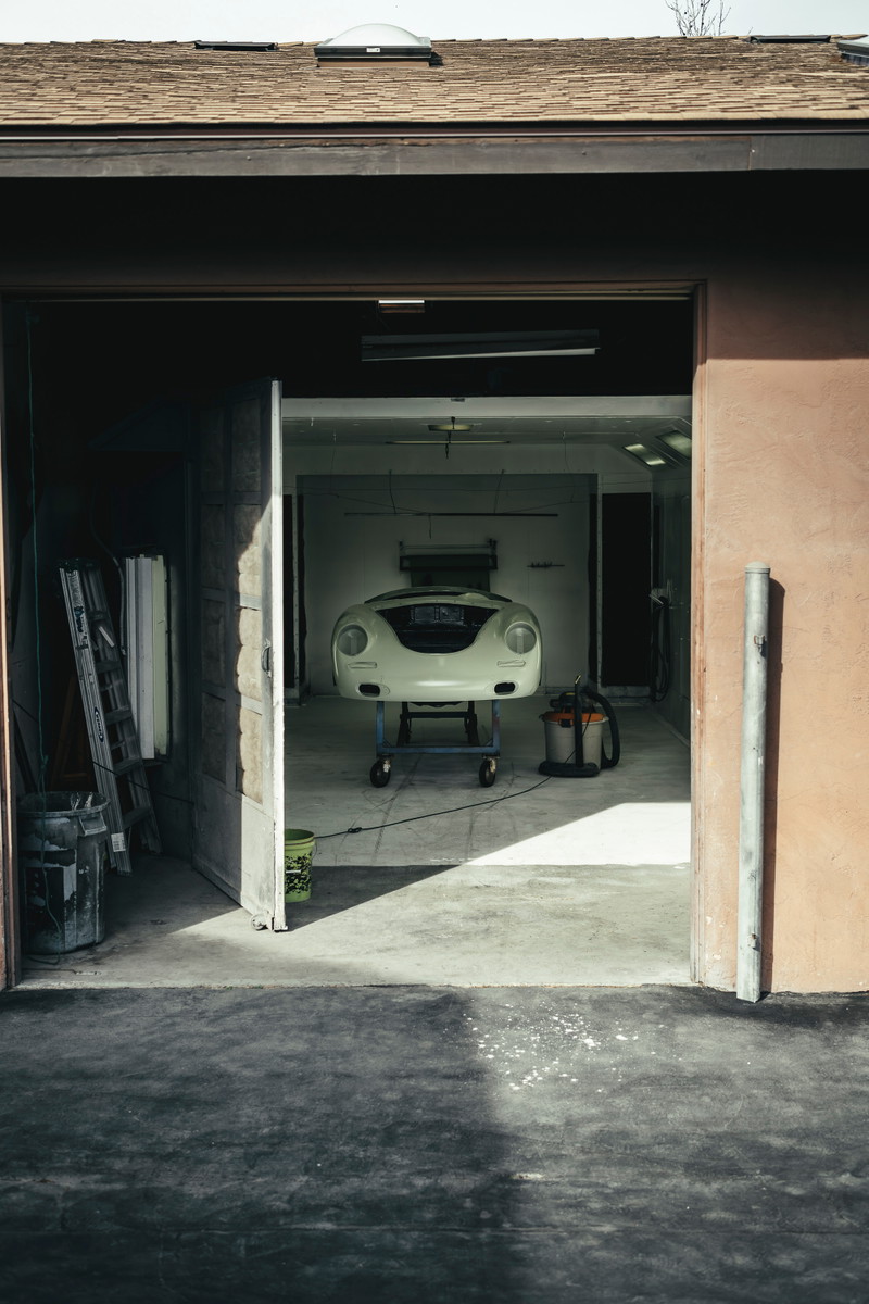 Front view of a creme white Porsche 356 body shell on a workshop cart, ready for restoration.