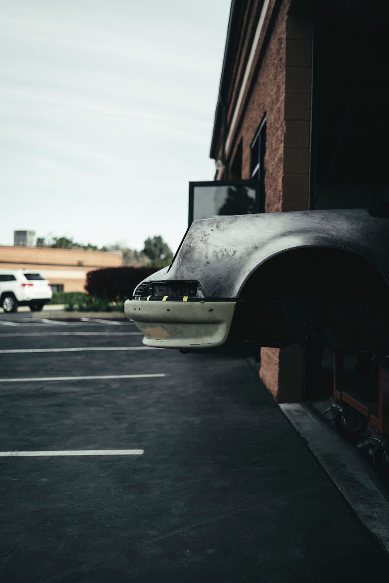 Air-cooled Porsche 911 front fender and bumper in bare metal and primer, undergoing custom restoration bodywork.