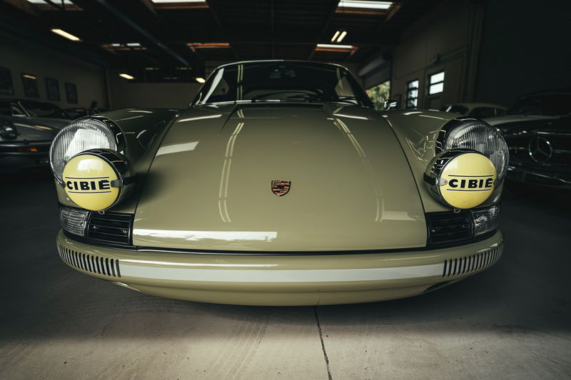 Front view of a classic '60s Porsche 911 in light green, featuring distinctive CIBIE rally lamps & white bumper livery.