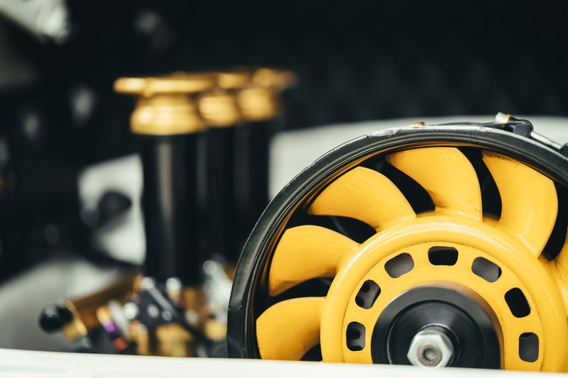 Detailed shot of a yellow Porsche 911 air-cooled engine cooling fan. Black fan housing and gold performance components visible.