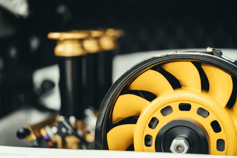 Detailed shot of a yellow Porsche 911 air-cooled engine cooling fan. Black fan housing and gold performance components visible.