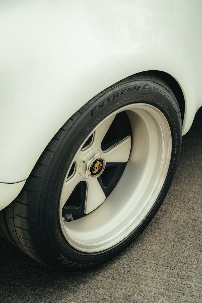 White classic Porsche rear wheel: Fuchs-style multi-piece rims with polished lip, Porsche crest centerlock, & Continental ExtremeContact tires.
