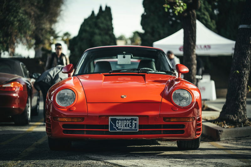 Front view of a Guards Red Porsche 959 supercar at the Los Angeles "Lit Show." Features "GRUPPE B" plate & iconic round headlamps.