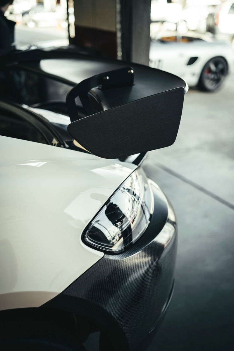 Close-up of a white Porsche 911 GT3 RS rear, showcasing its aggressive swan-neck rear wing and carbon fiber trim.