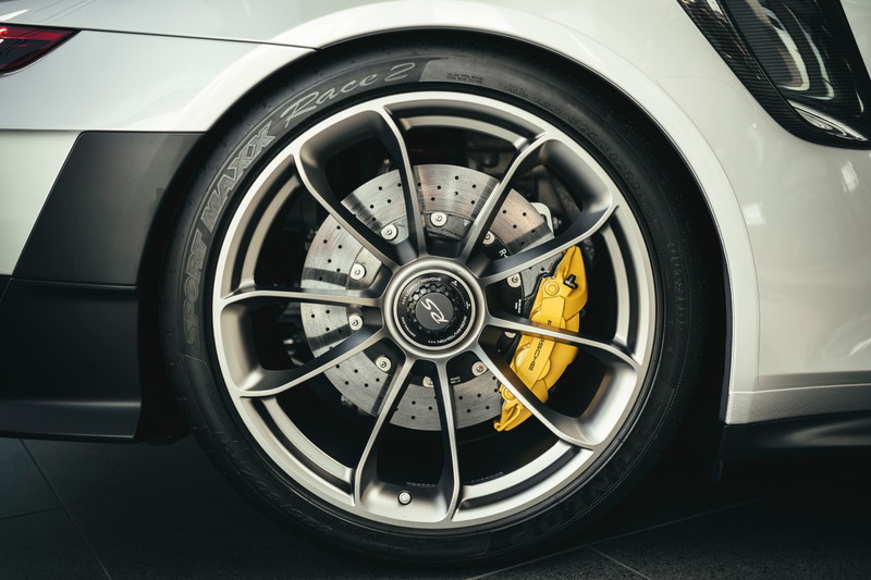White Porsche 911 GT3 RS rear multi-spoke rims, yellow PCCB calipers, drilled rotors, and black lower trim.