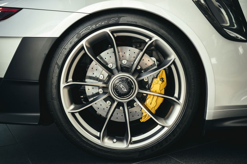 White Porsche 911 GT3 RS rear multi-spoke rims, yellow PCCB calipers, drilled rotors, and black lower trim.