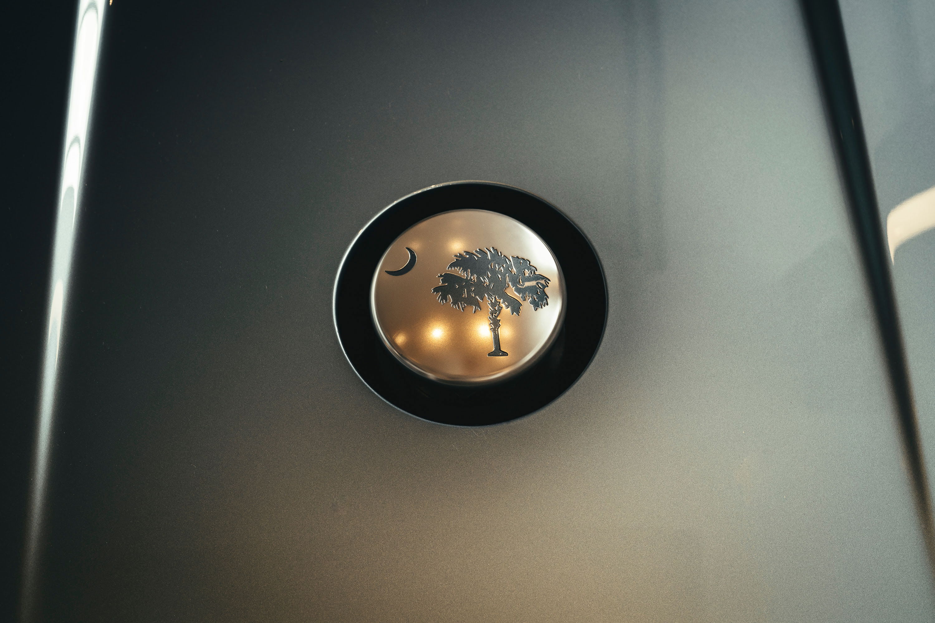 Bespoke Rolls-Royce: custom Palmetto & Crescent badge on luxurious dark metallic grey finish at LA's 'Lit Show'.