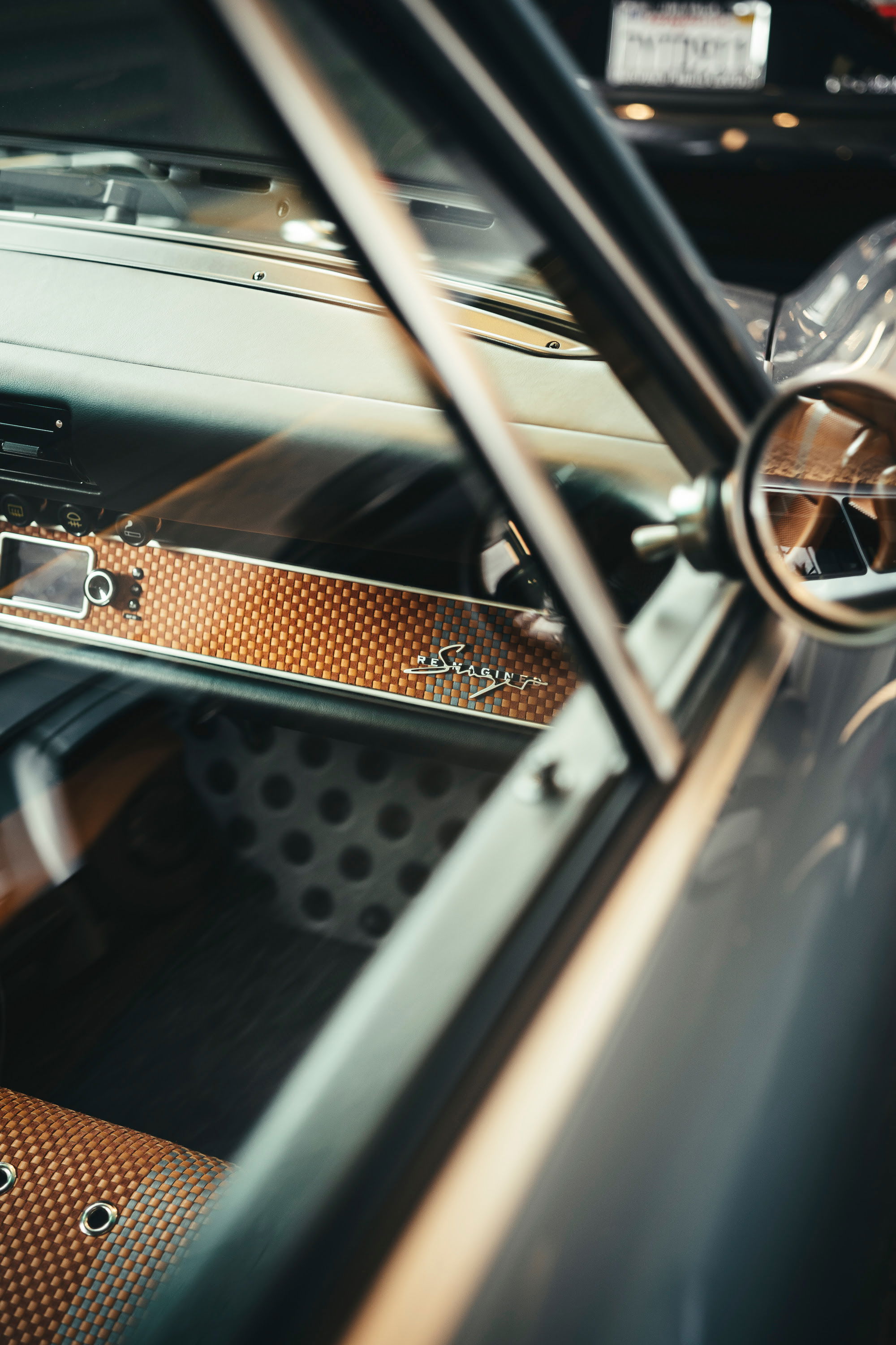 Interior shot of a bespoke Singer 911 with custom orange woven dashboard trim, "Singer" badge, and perforated details.