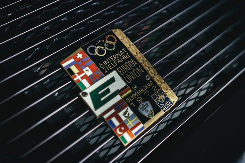Vintage 1972 Europa Union Olympic rally plaque on a classic black Porsche 911 engine lid grille.