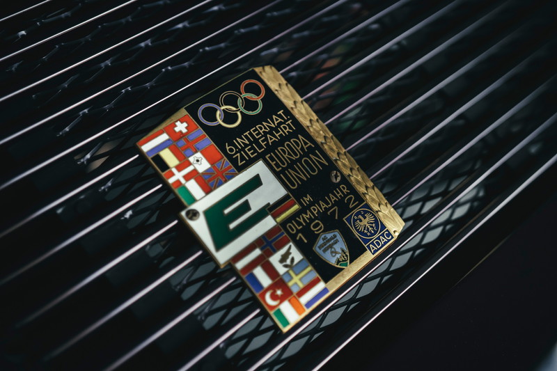 Vintage 1972 Europa Union Olympic rally plaque on a classic black Porsche 911 engine lid grille.