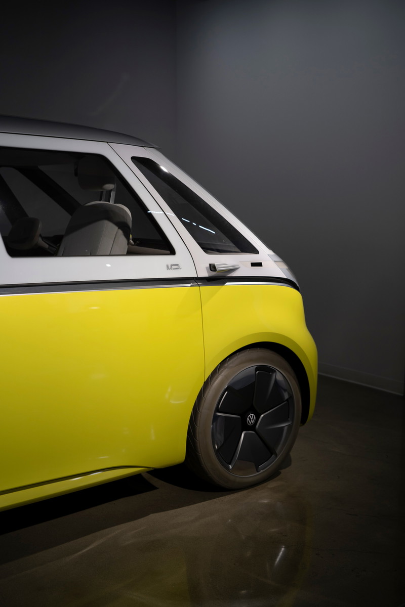 Front quarter view of a Volkswagen ID. Buzz in yellow and white two-tone livery, featuring black multi-spoke aero rims and silver body trim.