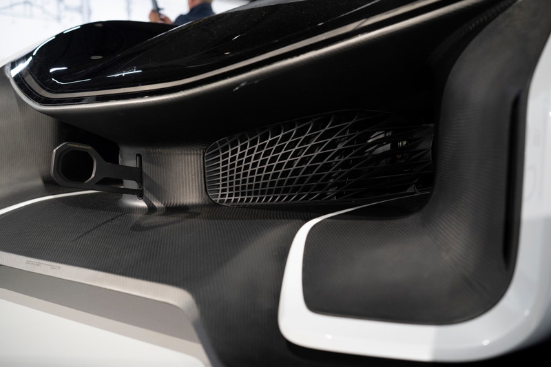 Rear view of a white & black supercar, featuring a single exhaust, intricate mesh vent, and carbon fiber rear diffuser.