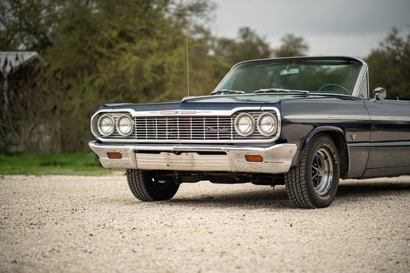 1964 dark blue Chevrolet Impala SS convertible with chrome trim and classic rims.