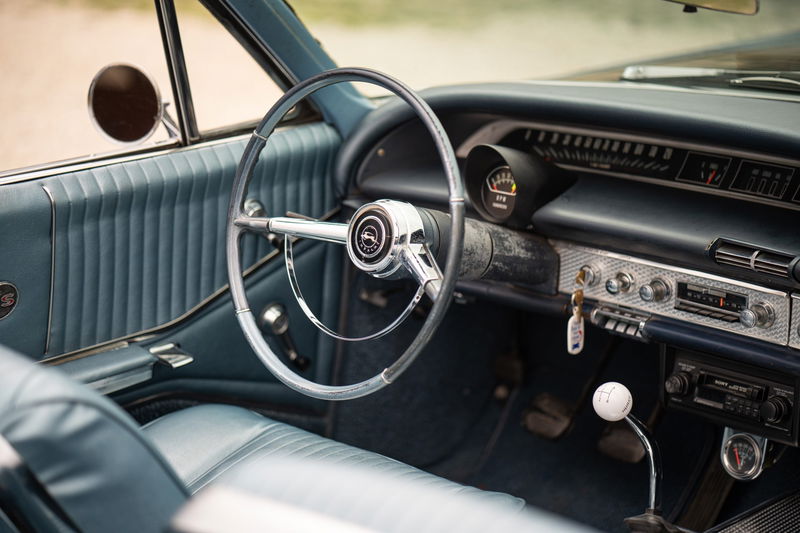 Interior of a 1964 Chevrolet Impala SS with blue vinyl trim and a chrome steering wheel.
