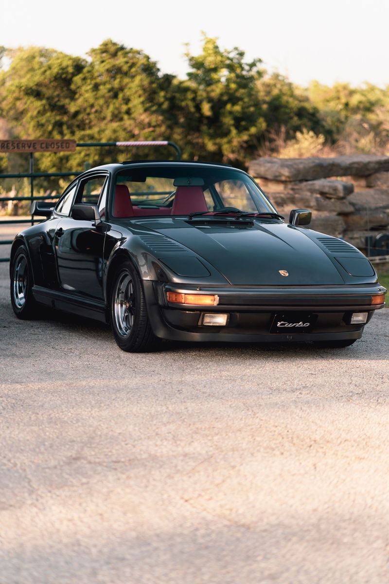 Dark grey 1989 Porsche 930 Turbo Flachbau with red interior and gold BBS rims.