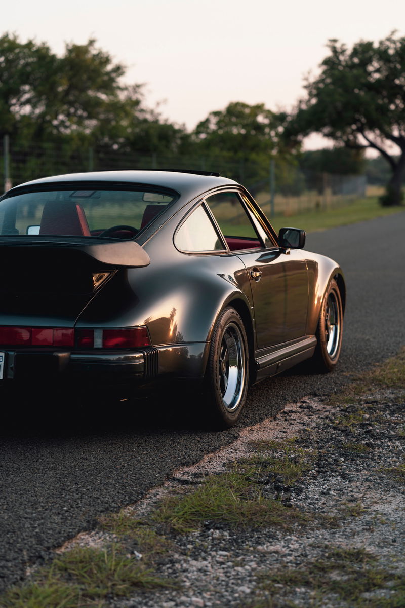Black 1989 Porsche 930 Turbo Flachbau coupe with red interior and Fuchs wheels.