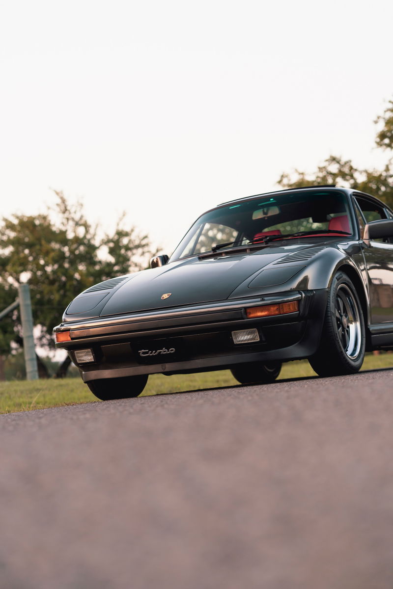 Black 1989 Porsche 930 Turbo Flachbau with red interior, chrome trim, and black rims.