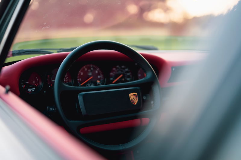 1989 Porsche 930 Turbo Flachbau interior with red trim and Porsche crest on steering wheel.