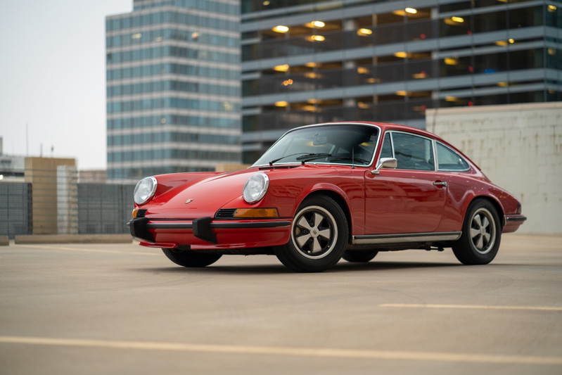 1973 Porsche 911S in Bahia Red with Fuchs rims, parked outdoors.