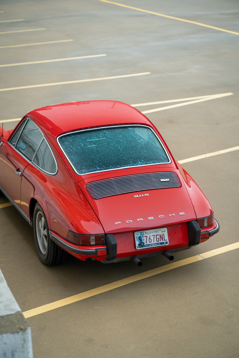 Red 1973 Porsche 911S with chrome trim and dual exhaust pipes.