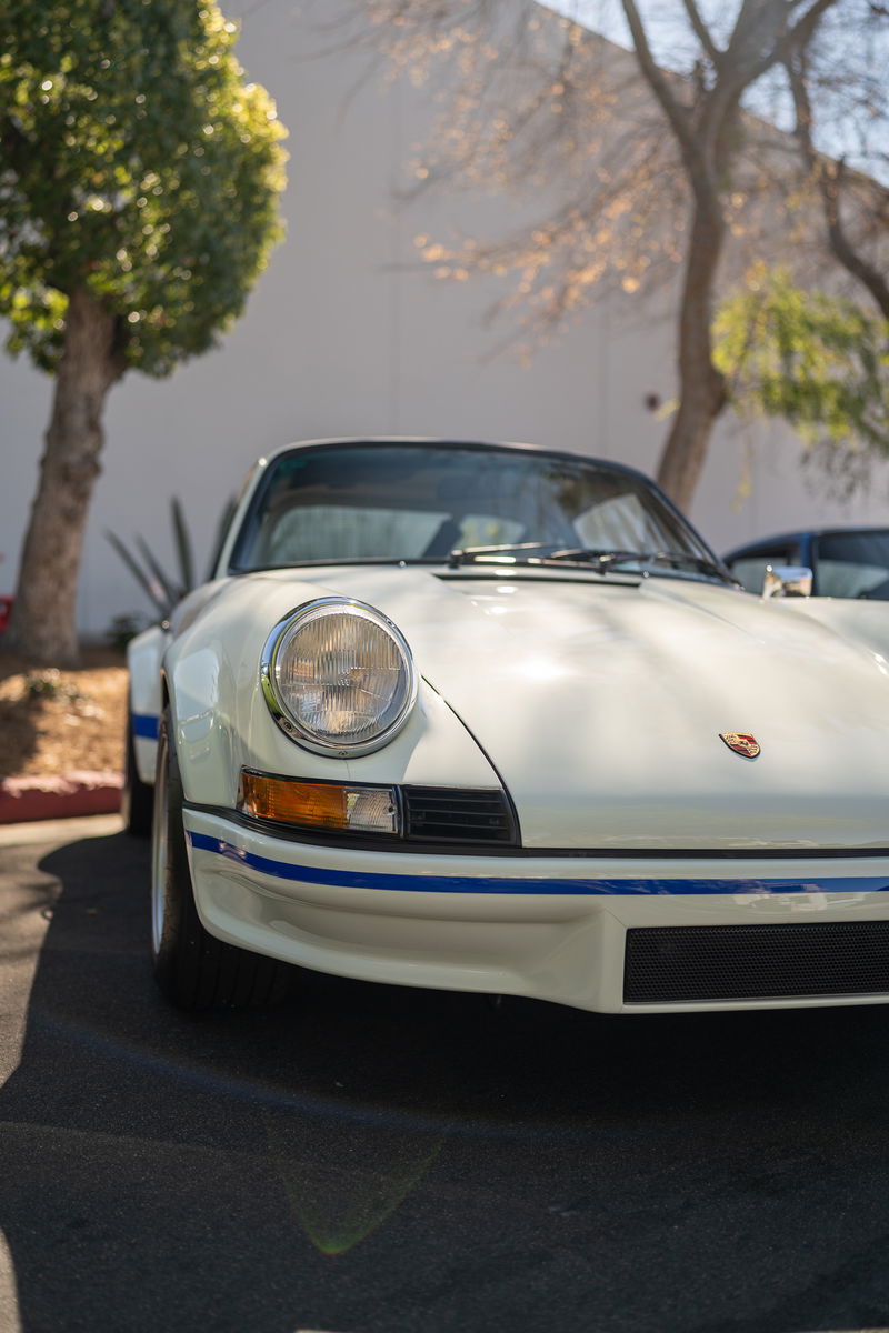 White classic Porsche 911 with blue livery trim and chrome rims.