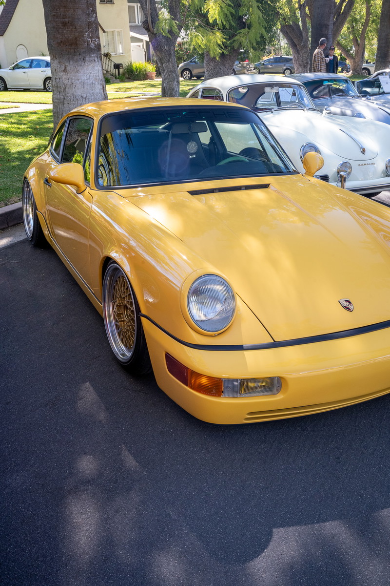 Yellow Porsche 911 (964) Carrera 2 with gold mesh rims and widebody trim.