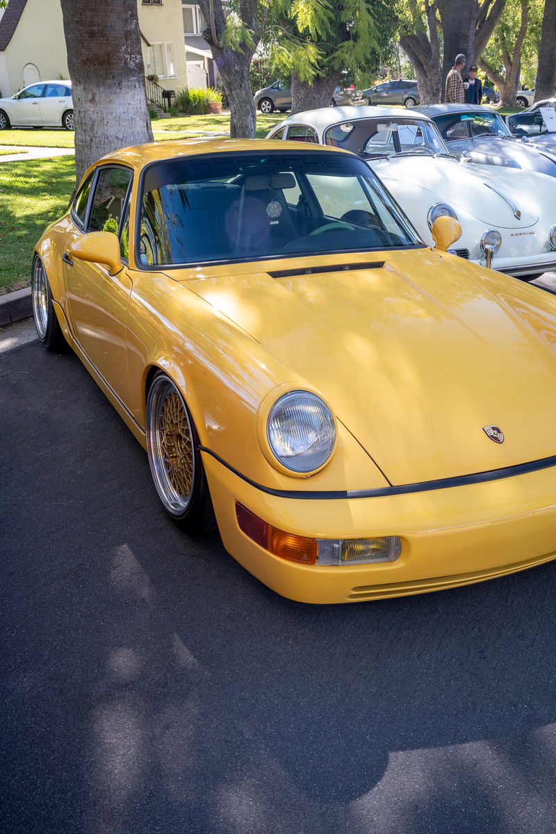 Yellow Porsche 911 (964) Carrera 2 with gold mesh rims and widebody trim.