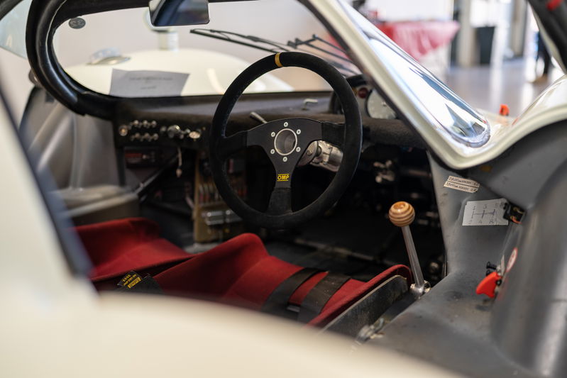 Vintage race car interior with OMP steering wheel and red racing seats.