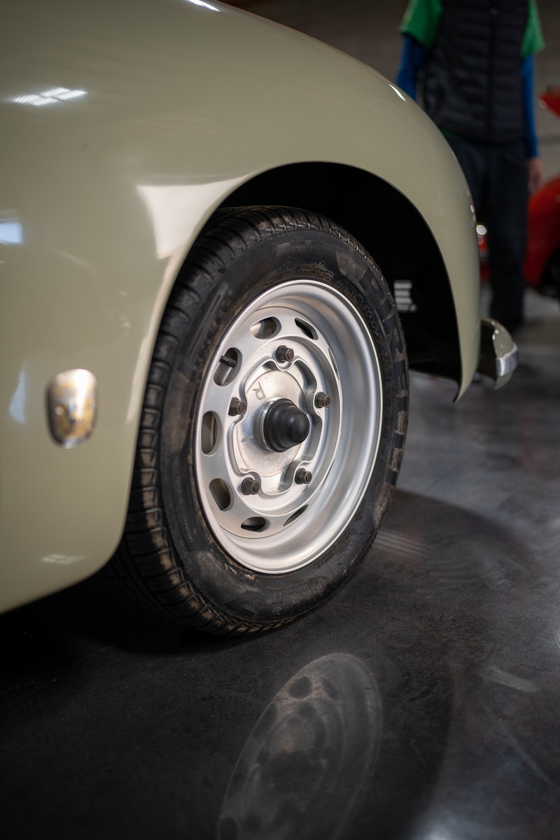Vintage Porsche 356 in pale green, showing a polished aluminum rim and tire detail.