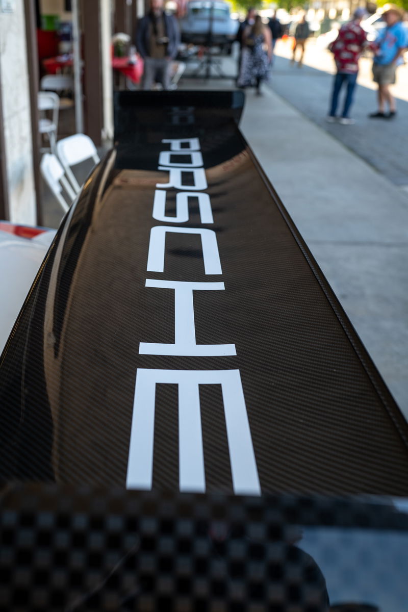 Close-up of a carbon fiber rear spoiler with white "PORSCHE" livery on a black Porsche.
