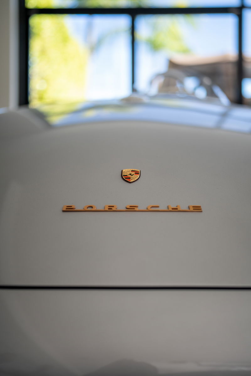 Close-up on a silver Porsche crest and "PORSCHE" script on the rear of the car.