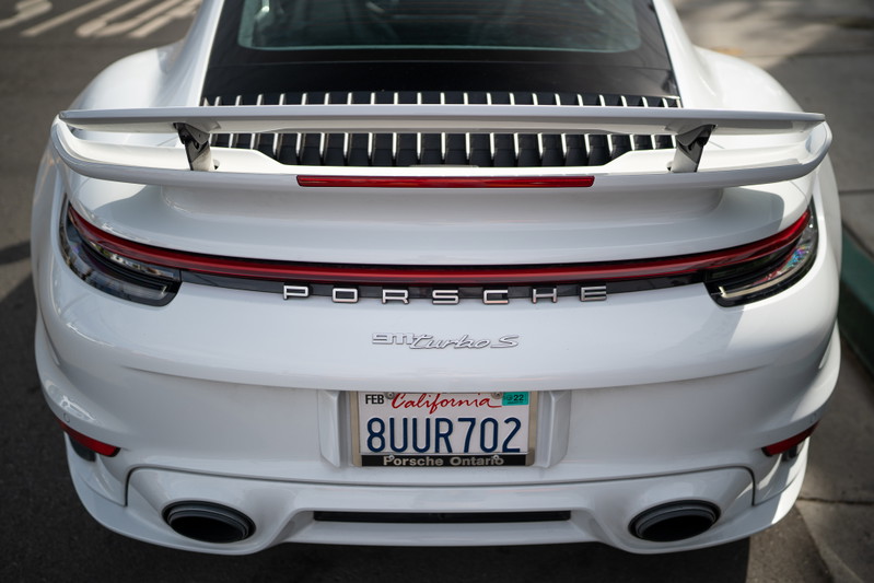 White Porsche 911 Turbo S rear with a large wing and quad exhaust tips.