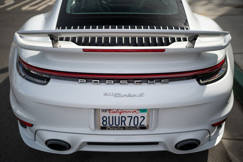 White Porsche 911 Turbo S rear with a large wing and quad exhaust tips.
