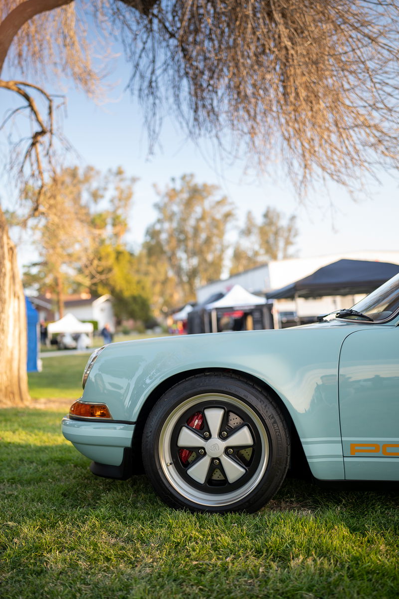Light blue Porsche 911 with Fuchs wheels and orange side livery.