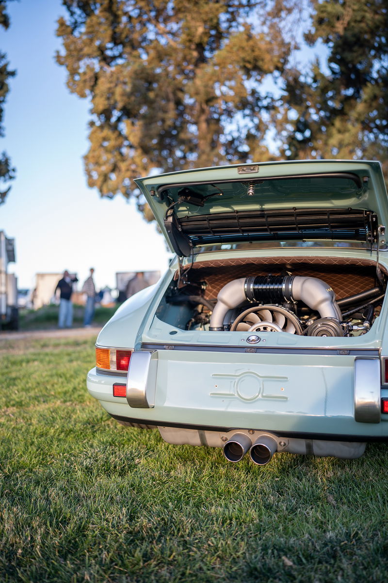 Light blue 1970s Porsche 911 with open engine lid, dual exhaust, and chrome trim.