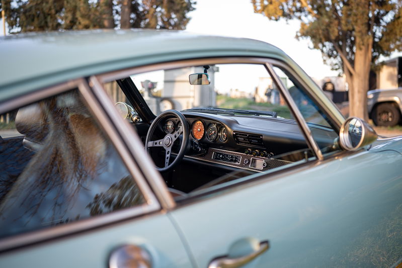Light blue vintage Porsche interior with a classic three-spoke steering wheel and gauges.
