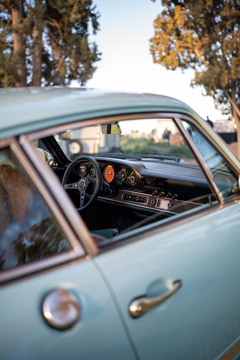 Light blue Porsche 911 interior with classic gauges and steering wheel.