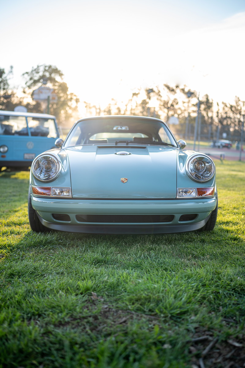 Light blue Porsche 911 front view in the grass.