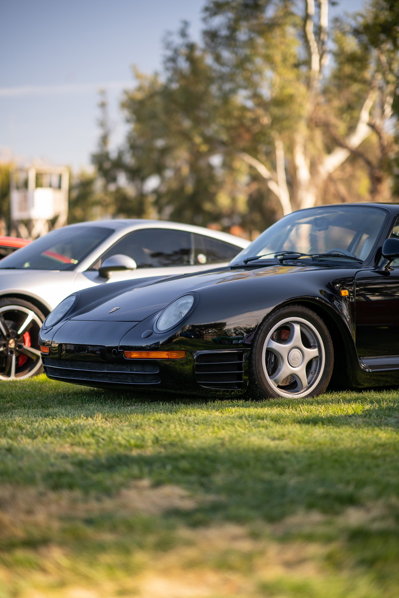 Black Porsche 959 with silver five-spoke rims parked on grass.