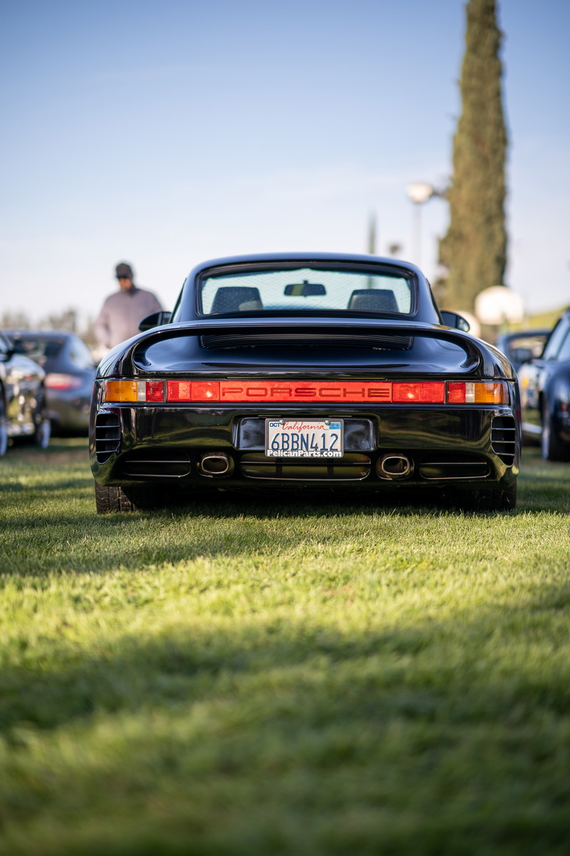 Black Porsche 959 with red "PORSCHE" script taillight bar and dual exhaust tips.