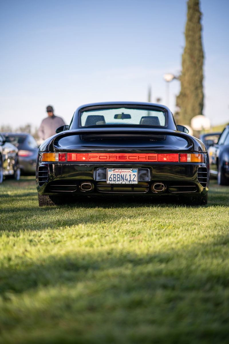 Black Porsche 959 with red "PORSCHE" script taillight bar and dual exhaust tips.