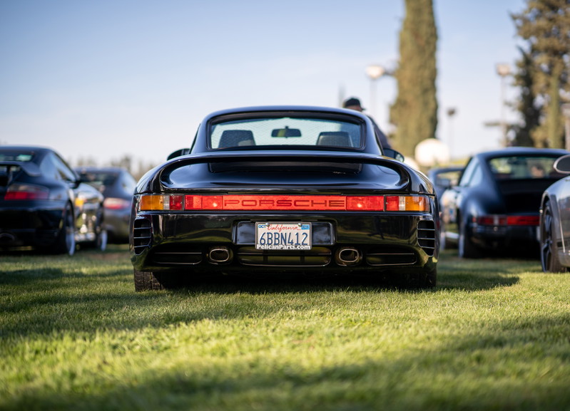 Rear view of a black Porsche 959 at a car show. California license plate 6BBN412.