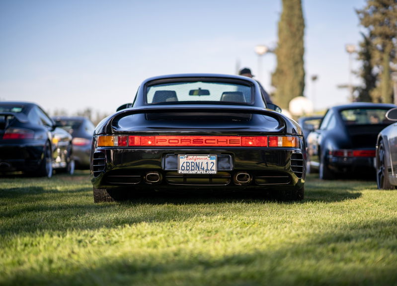 Rear view of a black Porsche 959 at a car show. California license plate 6BBN412.