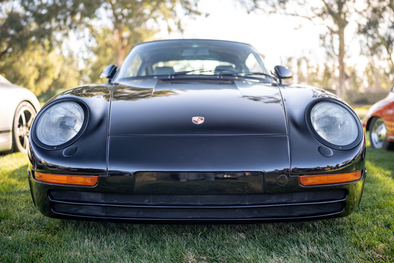 Black Porsche 959 front view, parked on grass during a car show.