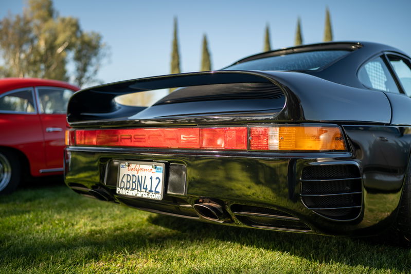 Black Porsche 959 rear view, with distinctive wing and horizontal taillights.