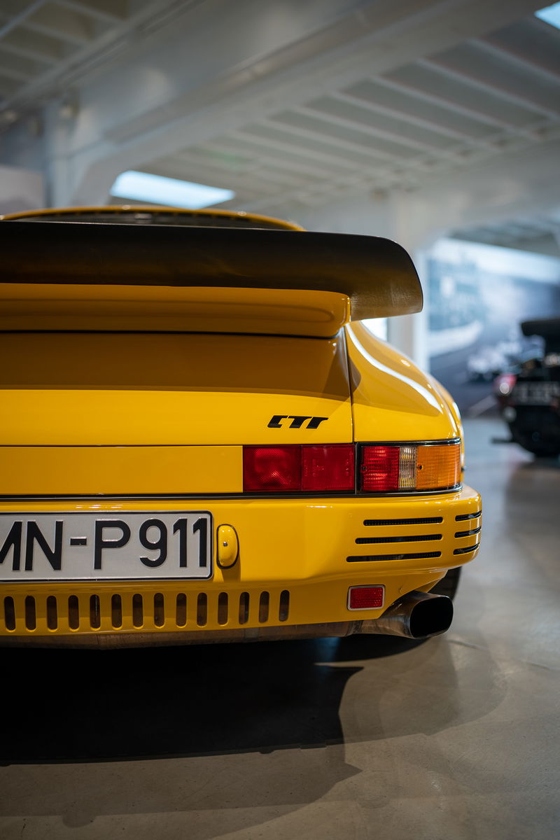 Yellow Porsche 911 Turbo with a large spoiler, "CTT" badge, and custom license plate.